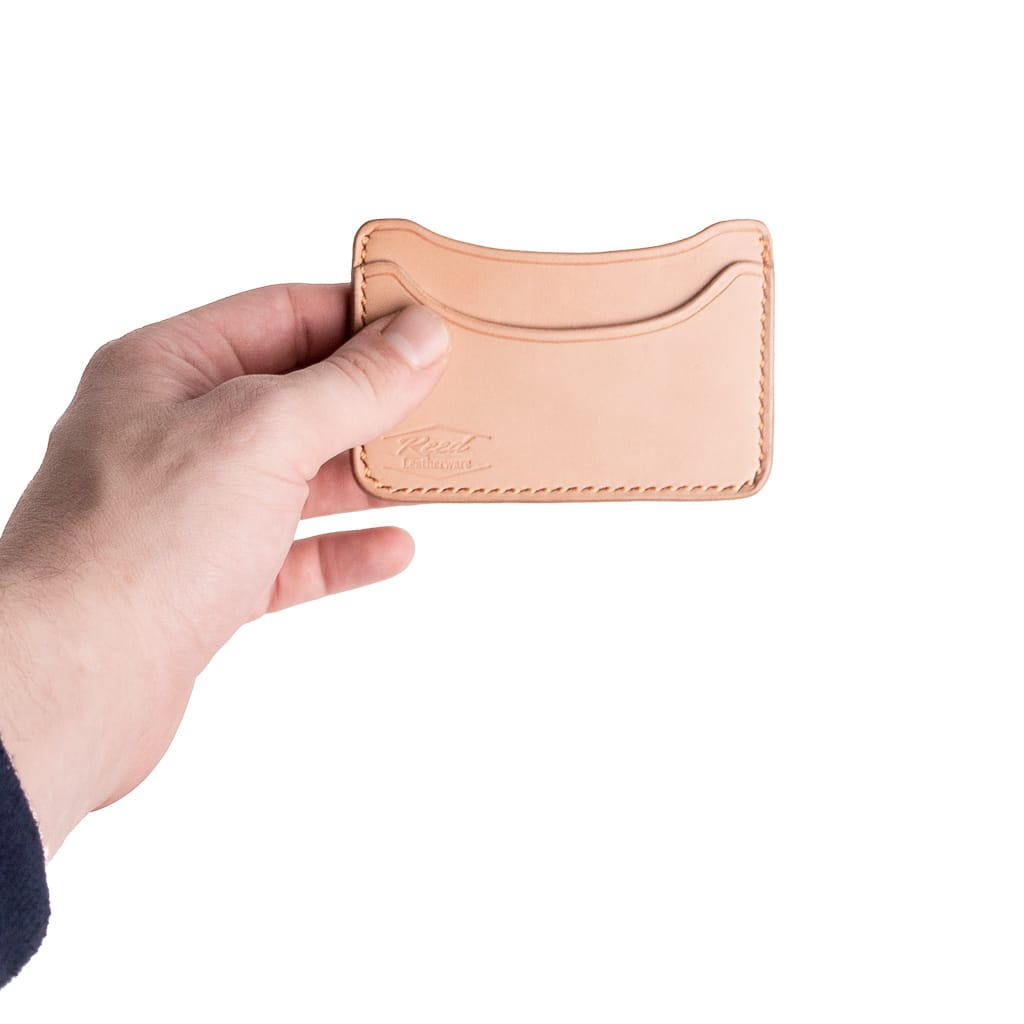 veg tan wallet held on white background for size comparison. the wallet is smaller than a human hand. 