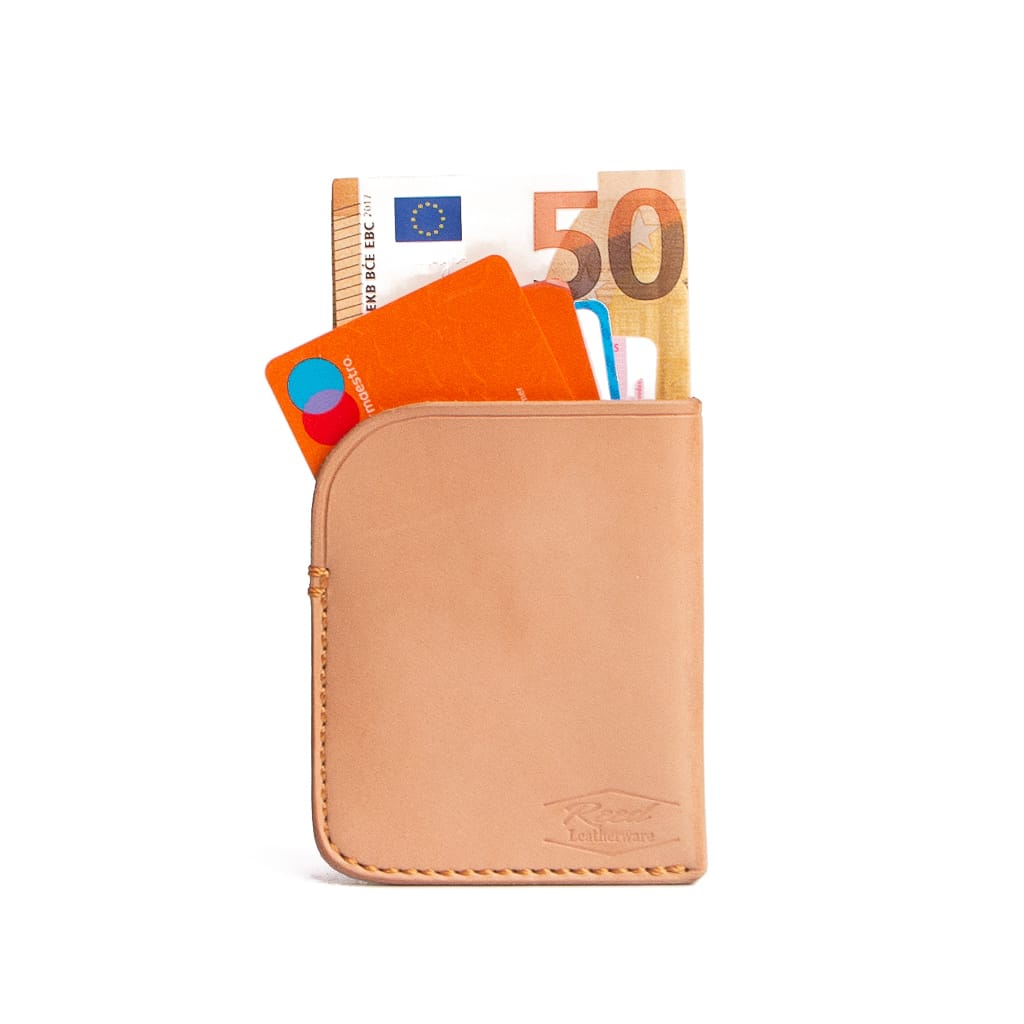 Vegetable tanned minimalist wallet with money and cards spilling out on a white background. Glorious. 